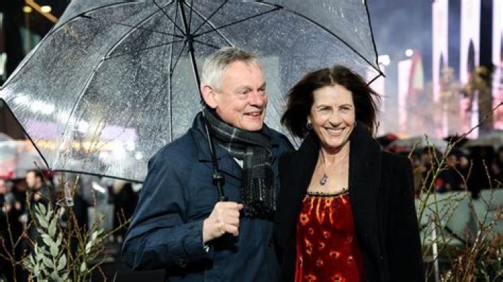 Date night: Martin could be seen smiling as he posed on the red carpet alongside his girlfriend Rachel who wore a bright red trouser suit with black buttons