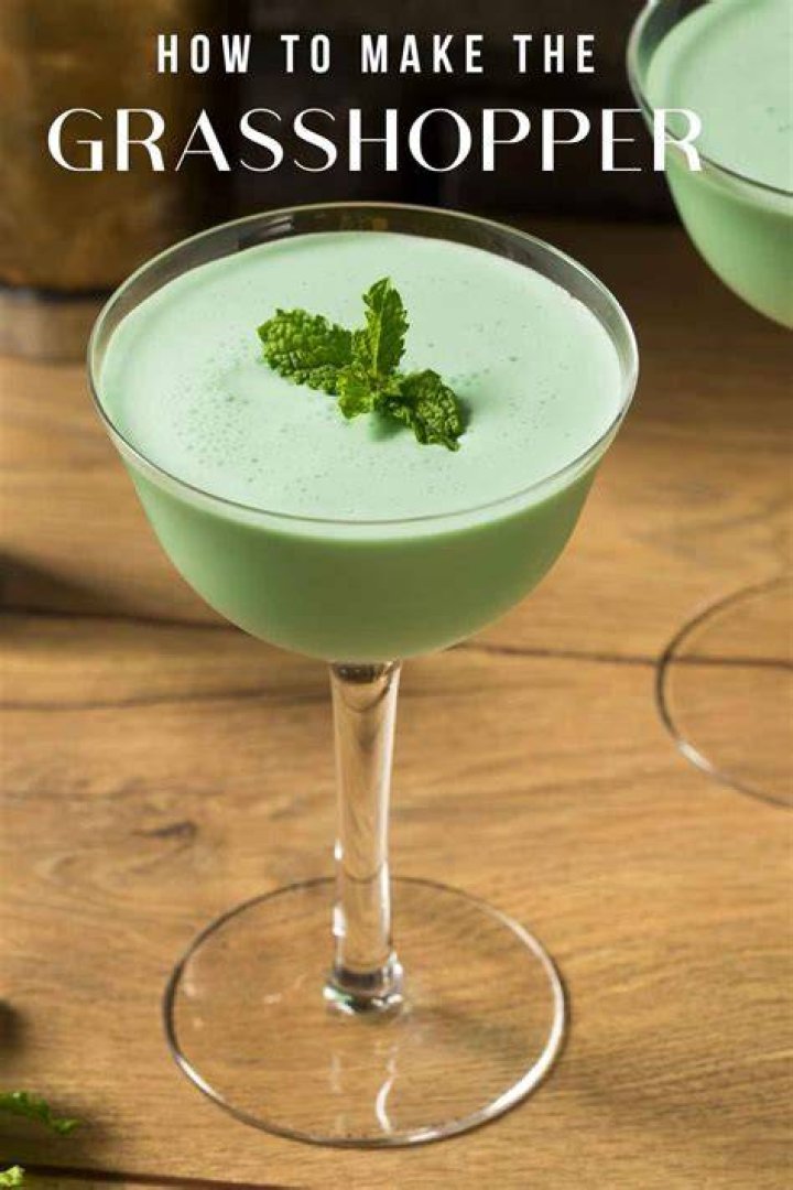 Green grasshopper drink in a stemmed glass with swirled with chocolate syrup.