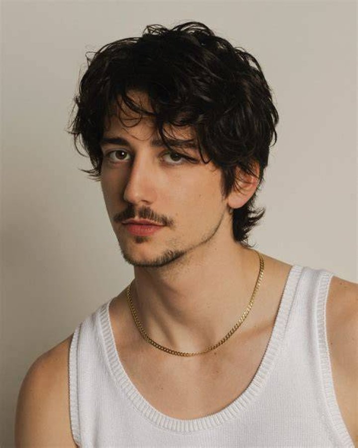 Milo Manheim in a white top poses for a picture.
