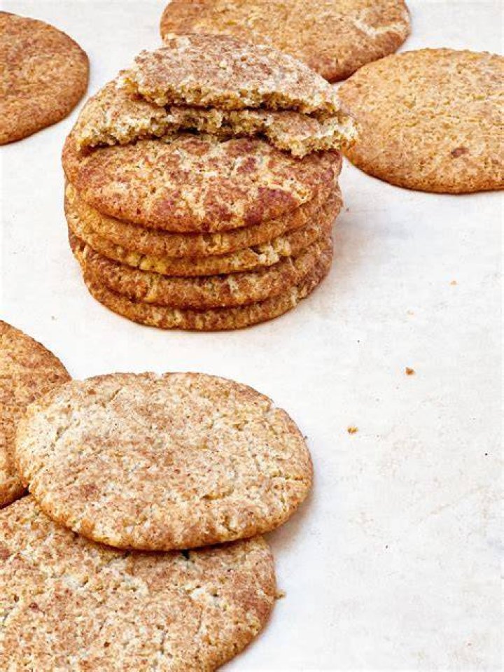 Stack of four maple snickerdoodle cookies with cinnamon sticks in the background.
