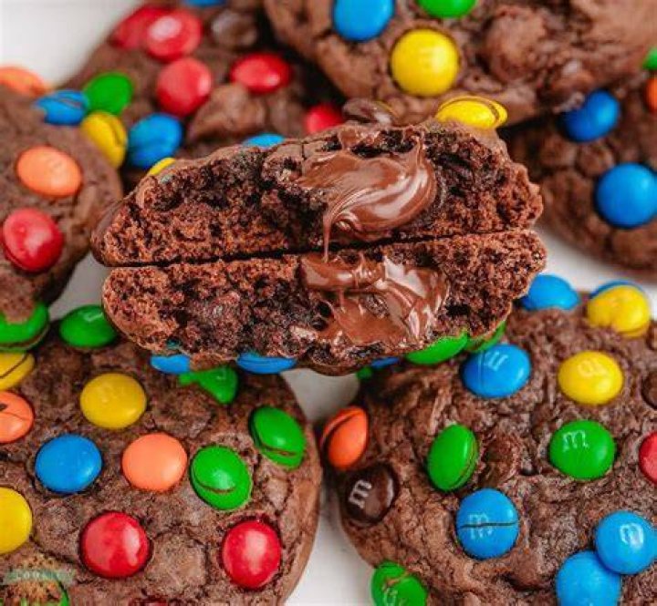 Stack of M&M cookies with white chocolate chips and pastel sprinkles.