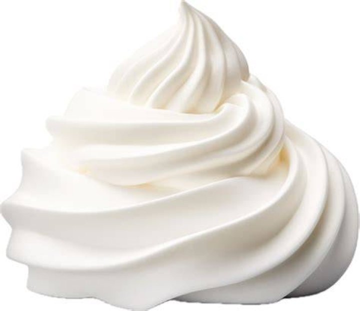 Whipped cream in a white bowl with strawberries.
